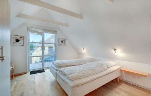 a white bedroom with a bed and a window at Hus R in Henne Strand