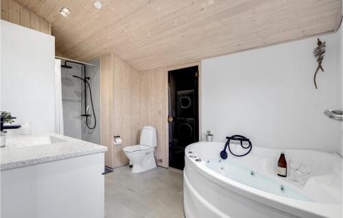 a white bathroom with a tub and a toilet at Stunning Home In Blokhus With 3 Bedrooms, Sauna And Wifi in Blokhus
