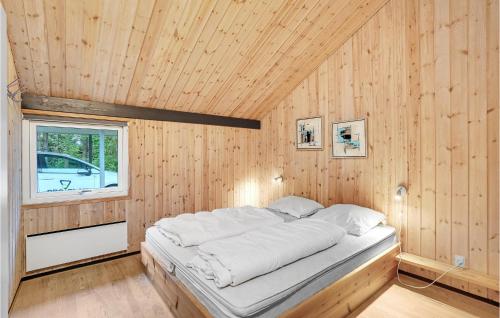 a bed in a wood paneled room with a window at 4 Bedroom Stunning Home In Oksbl in Ovtrup