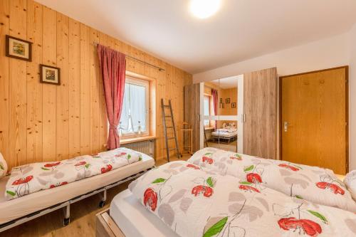two beds in a room with wooden walls at Casa Sara in Pozza di Fassa