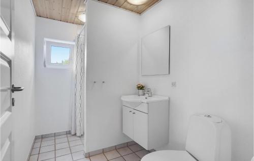 a white bathroom with a toilet and a sink at Holiday Home Vester Storetoft Fanø I in Sønderho