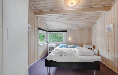 a bedroom with a large bed in a room with wooden walls at Cozy Home In Jerup With Kitchen in Jerup