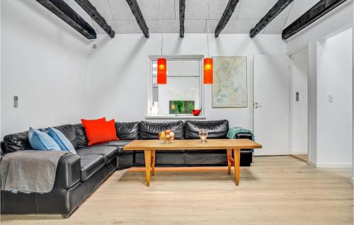a living room with a black leather couch and a wooden table at 4 Bedroom Lovely Home In Knebel in Knebel