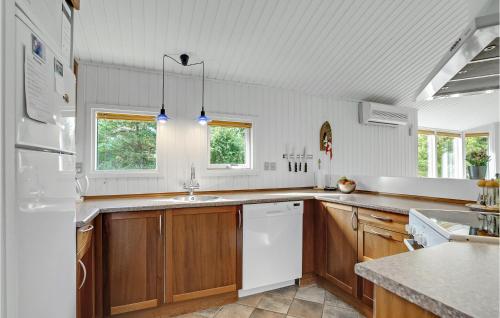 a kitchen with wooden cabinets and a white refrigerator at Stunning Home In Fjerritslev With Sauna in Fjerritslev