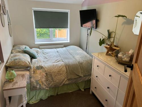 a bedroom with a bed and a dresser and a television at Modern family home central Cheltenham in Cheltenham