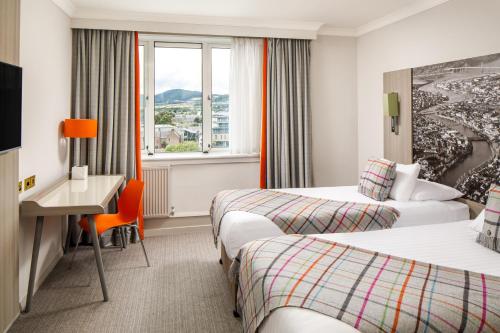 a hotel room with two beds and a desk and a window at Mercure Inverness Hotel in Inverness