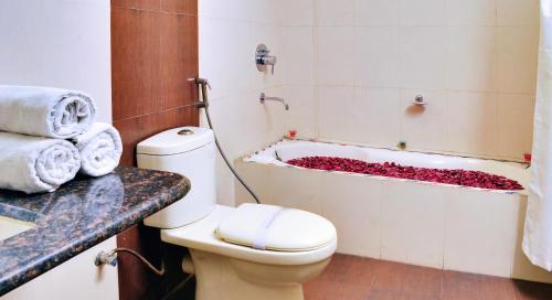 a bathroom with a toilet and a bathtub filled with flowers at Regal Hotel in Ajmer