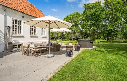 a patio with an umbrella and furniture on a lawn at Rimersgaard in Horslunde