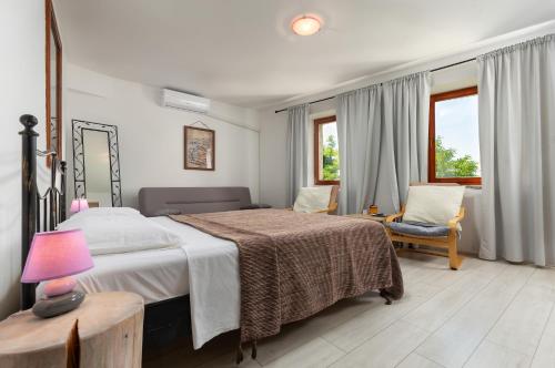 a bedroom with a bed and a chair and windows at Villa Borgo B&B in Motovun