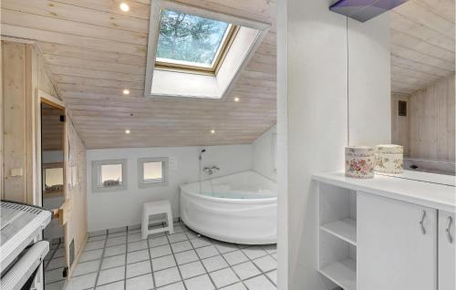 SpidsegårdにあるBeautiful Home In Nex With Saunaのバスルーム(バスタブ、シンク付)、窓が備わります。