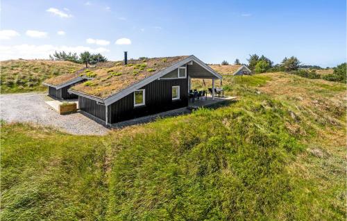 a black house with a grass roof on a hill at Awesome Home In Blokhus With Wifi in Blokhus