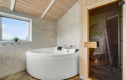 ein Badezimmer mit einer großen Badewanne und einem WC in der Unterkunft 4 Bedroom Gorgeous Home In Brkop in Børkop