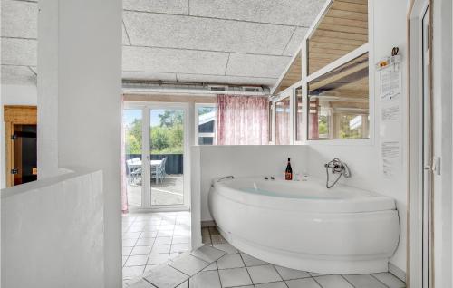 ヒアツハルスにあるAwesome Home In Hirtshals With 4 Bedrooms, Sauna And Wifiの白いバスルーム(バスタブ付)、窓が備わります。