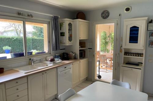 une cuisine avec des armoires blanches, une table et une fenêtre dans l'établissement Duplex house with private pool near the sea, à Lanton