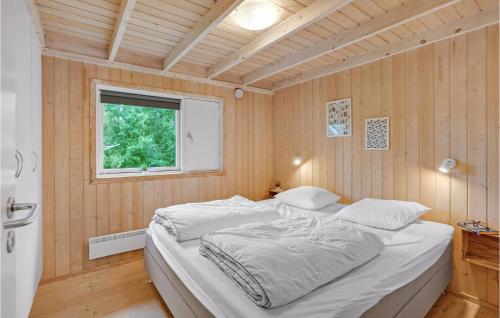 een bed in een kamer met houten wanden en een raam bij Stunning Home In Rdby With 3 Bedrooms And Wifi in Kramnitse