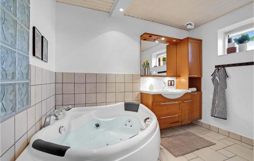 a bathroom with a white tub and a sink at Beach Front Home In Vggerlse With House Sea View in Væggerløse