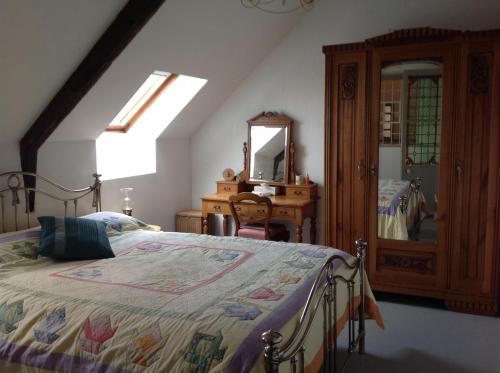 Schlafzimmer mit einem Bett, einer Kommode und einem Spiegel in der Unterkunft La Cheneraie, A Peaceful, Rural Retreat in Ménéac