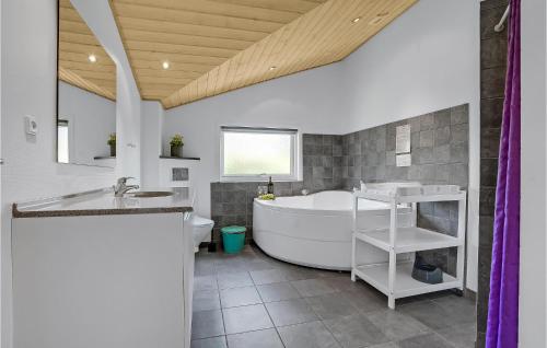 a bathroom with a tub and a sink and a toilet at 4 Bedroom Beautiful Home In Blvand in Blåvand