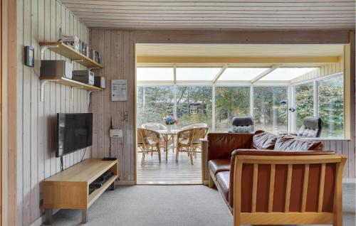 a living room with a couch and a television and a table at Holiday Home Østersvej Glesborg X in Fjellerup Strand