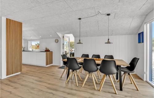 a dining room with a wooden table and black chairs at Three-Bedroom Holiday Home In Hvide Sande in Havrvig