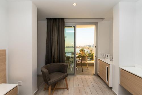 a living room with a chair and a balcony at Evalena Beach Hotel in Protaras