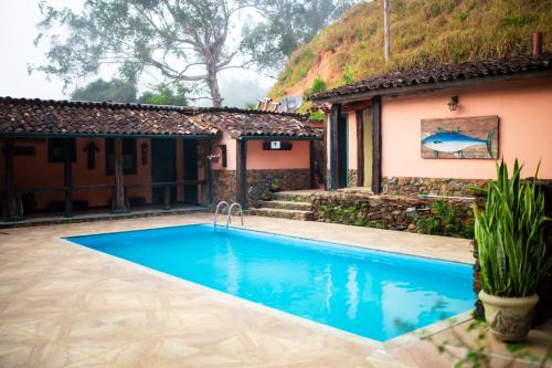 a swimming pool in front of a house at Hotel Fazenda Pirapetinga 