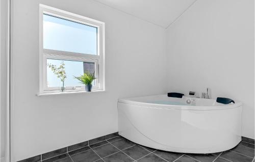 FlovtにあるNice Home In Haderslev With 4 Bedrooms And Wifiの白いバスルーム(白いバスタブ付)、窓が備わります。