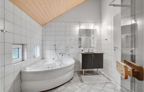 ein weißes Bad mit einer Badewanne und einem Spiegel in der Unterkunft Stunning Home In Hvide Sande With House A Panoramic View in Havrvig