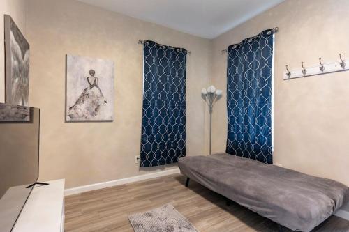 a living room with a bed and blue curtains at Pretty Blue Bungalow in Carondelet