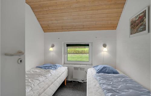 Amazing Home In Vinderup With 4 Bedrooms, Wifi And Indoor Swimming Pool في Vinderup: سريرين في غرفة صغيرة مع نافذة