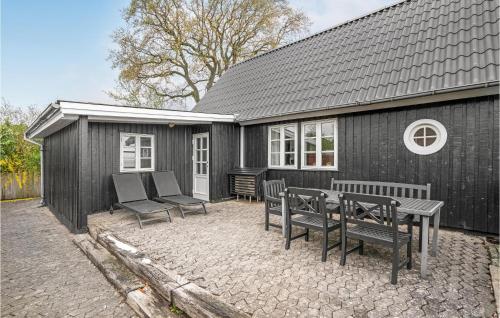 a black house with a table and chairs in front of it at Mosvig in Sønder Bjert