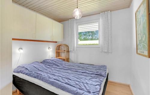 a bedroom with a bed with a blue comforter and a window at Gorgeous Home In Hejls With Kitchen in Hejls