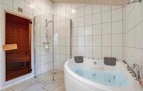 bagno bianco con vasca e doccia di Cozy Home In Rdby With Sauna a Kramnitse