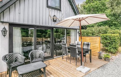 a wooden deck with a table and chairs and an umbrella at Holiday Home Vestre Strandvej Nexø Iii in Balke