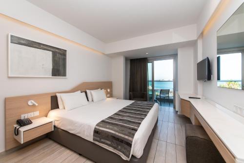 a hotel room with a bed and a tv at Evalena Beach Hotel in Protaras