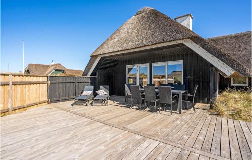 a deck with chairs and a table and a thatch roof at Holiday Home Sydslugen Blåvand Ii in Blåvand