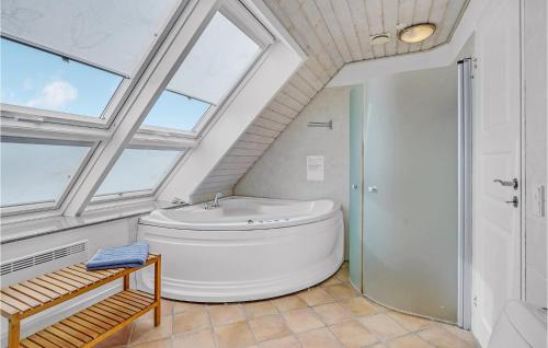 La salle de bains est pourvue d'une grande baignoire blanche et de fenêtres. dans l'établissement Beautiful Home In Rm With Wifi, à Havneby