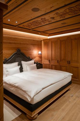 a bedroom with a large white bed with a wooden ceiling at The Falcon in Lech am Arlberg