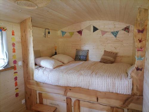 1 cama en una habitación en una cabaña de madera en Roulotte La Vert-Dîne, en Saint-Pardoux