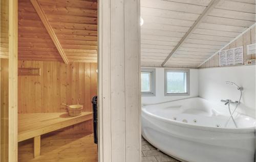 baño con bañera blanca grande y paredes de madera. en Lovely Home In Sjlund With House Sea View, en Hejls