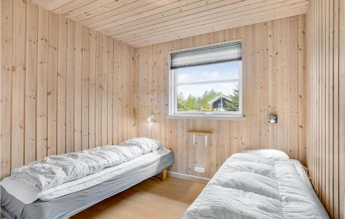two beds in a room with wooden walls and a window at Gorgeous Home In Idestrup With Sauna in Marielyst