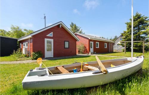 a white boat sitting in the grass in front of a house at Holiday Home Nørre Nebel 9 in Nymindegab