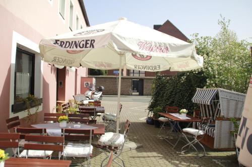 un patio con mesas, sillas y una sombrilla en Hotel Matheisen en Colonia