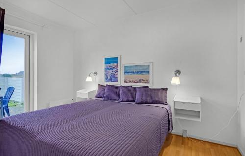Amazing Apartment In Rudkbing With Kitchen في رودكوبينغ: سرير أرجواني مع وسائد أرجوانية في غرفة بيضاء