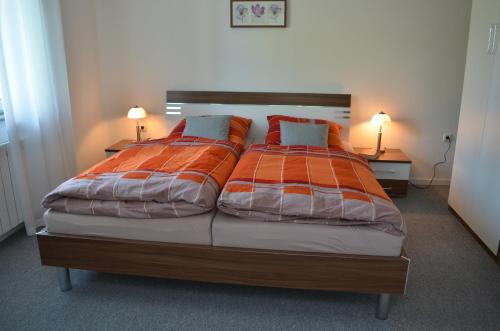 a bedroom with a large bed with orange and white sheets at Ferienwohnung Fam Wernicke in Preußisch Oldendorf