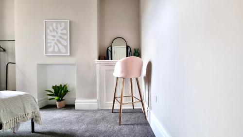 a pink chair in a room with a fireplace at Moorland House by Switchback Stays in Cardiff