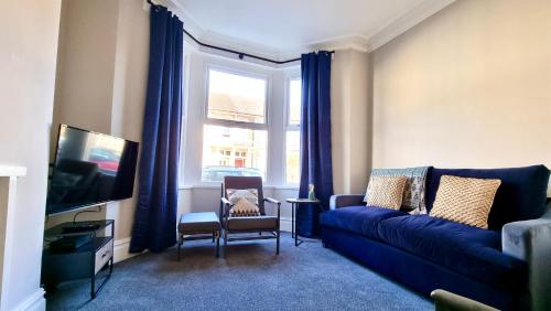 a living room with a blue couch and a window at Moorland House by Switchback Stays in Cardiff