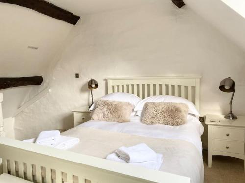 a bedroom with a white bed with towels on it at Charming Cottage in Heart of Bourton-on-the Water in Bourton on the Water
