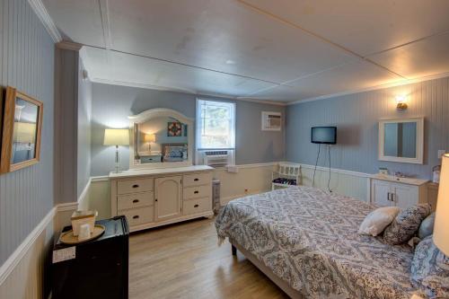 a bedroom with a bed and a dresser and a television at Blackbeard's Lodge in Ocracoke
