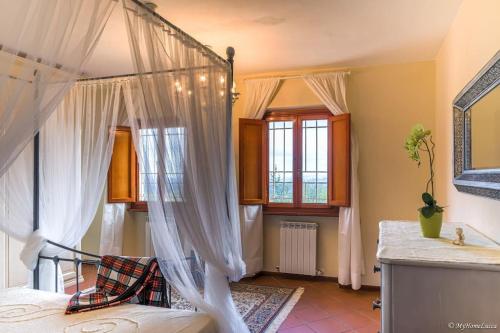 a bedroom with a canopy bed with white curtains at Villa Malula a classy house in the countryside in Capannori